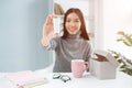 Nice picture of attractive girl sitting at the table and showing the beauty product to the camera. It is hand cream