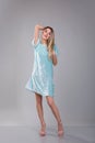 Nice picture of young blonde girl dressed in blue dress looking at the camera against grey background Royalty Free Stock Photo