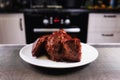 Nice piece of meat on plate. Roast beef close-up. Barbecue meat in modern kitchen. Blurred background oven. Hot cooked dinner. Royalty Free Stock Photo