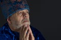 Portrait of senior man wearing blue oriental clothes looking up against dark background Royalty Free Stock Photo