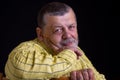 Smiling senior man in yellow shirt leant elbow on a back of chair against dark background