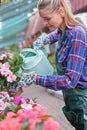 Lovely happy young woman gardener choosing flower pot with anthuriums in garden center Royalty Free Stock Photo