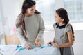 Nice positive woman teaching her daughter to make clothes