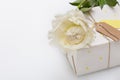 Nice present packed in white paper with small yellow stars with beautiful peony flower on white wooden background. Wrapped gift Royalty Free Stock Photo