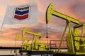 Nice pumpjack oil extraction and cloudy sky in sunset with the CHEVRON United States of America flag USA SLB 3D rendering Royalty Free Stock Photo