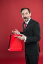 Nice purchase. Shocking discount. Mature businessman hold paper bag gift red background. Shopping concept. Christmas