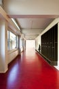 Interior of a school with long corridors with red floors.