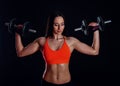 Nice girl doing workout with dumbbells isolated over black background. Athletic young woman do a fitness workout with weights