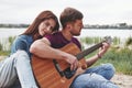 Nice skills. Man plays guitar for his girlfriend at beach on their picnic at daytime Royalty Free Stock Photo