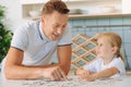 Nice smart girl collecting puzzles with her father