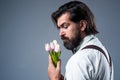 nice smell. fathers day. mature retro man. bearded man in suspenders smell flowers. brutal guy ready for romantic date Royalty Free Stock Photo