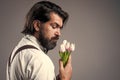 nice smell. fathers day. mature retro man. bearded man in suspenders smell flowers. brutal guy ready for romantic date Royalty Free Stock Photo