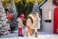 Nice smiling children and adorable pony with festive wreath near the small wooden house and snow-covered trees. New Year and Chris Royalty Free Stock Photo