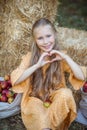 Nice smiling girl with blue eyes and blonde hair shows a heart with her hands