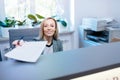 A nice, smiling woman at the reception desk, office, notary office gives the documents