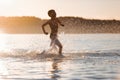 Beautiful sunrise. On the nice sunny summer day the small boy is playing, running, jumping at the lake. Happy moments of childhood Royalty Free Stock Photo