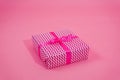 Nice surprise gift packed in stylish pink and white paper with fuchsia bow on pink background with copy space