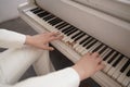 Close up of teenager arms with old white grand piano. person in white clothes plays music.