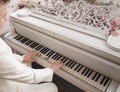 Close up of teenager arms with old white grand piano. person in white clothes plays music.