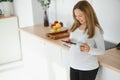 So nice to hear you Beautiful young pregnant woman talking on phone and looking away with smile while standing at kitchen interior Royalty Free Stock Photo