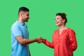 Nice to meet you! Portrait of happy young couple in casual wear shaking hands. isolated on green background Royalty Free Stock Photo