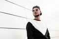 Nice urban young hipster man in stylish sweatshirt in black trendy black baseball cap in sunglasses in the city. Handsome guy Royalty Free Stock Photo