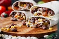 Nice vegetarian burrito over black table on wooden board.