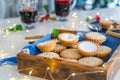 Nice warm cosy composition of traditional english festive pastry mince pies in wooden tray with mulled wine drinks and lights