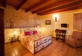 Nice warm interior of bedroom in a rustic style in country house or hotel. Wooden beams and walls made of natural stone. Royalty Free Stock Photo