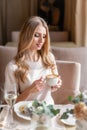 Nice woman eat breakfast in cafe. Portrait of young charming female drinking coffee and toasted sandwich in modern Royalty Free Stock Photo