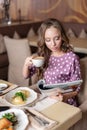 Nice woman eat breakfast in cafe. Reading a magazine. Portrait of young charming female drinking coffee and eat eggs Royalty Free Stock Photo