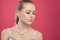 Nice woman wearing trendy gold jewelry earrings necklace with pearls on colorful pink background
