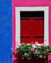 Nice wooden window with flowers and bright blue, red, pink and white colors, Burano, Venice, Italy Royalty Free Stock Photo