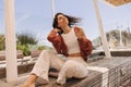 Nice young caucasian girl waving her hair, sits on wooden bench in sunny weather. Royalty Free Stock Photo