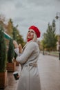 Pretty  young woman in white coat and red beret look back. Royalty Free Stock Photo