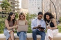 Nice young interracial college students studying on laptop, preparing for exam sitting outdoors.