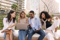 Nice young interracial students looking at laptop screen browsing presentation sitting outside.