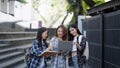 Nice young students use laptop after class sitting outdoors. girls wear casual clothes in spring. Concept of modern Royalty Free Stock Photo