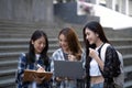 Nice young students use laptop after class sitting outdoors. girls wear casual clothes in spring. Concept of modern Royalty Free Stock Photo