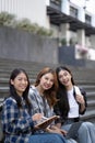 Nice young students use laptop after class sitting outdoors. girls wear casual clothes in spring. Concept of modern Royalty Free Stock Photo