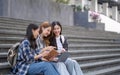Nice young students use laptop after class sitting outdoors. girls wear casual clothes in spring. Concept of modern Royalty Free Stock Photo