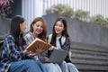 Nice young students use laptop after class sitting outdoors. girls wear casual clothes in spring. Concept of modern Royalty Free Stock Photo