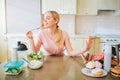 Nice young well-built model eting healthy food in kitchen at table. She says no to junk meal. Alone in kitchen. Daylight