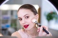 Nice young woman putting on decorative cosmetics Royalty Free Stock Photo