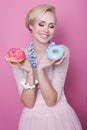 Nice young women hold colorful donuts. Soft colors