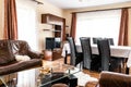 Nicely furnished sitting room with brown sofas and a glass table inside of a modern house