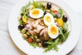 nicoise salad with tuna, eggs, and olives on a white plate