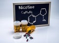 Nicotine written by hand on a whiteboard next to bottles of capsules