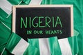 Nigeria in our hearts. Text on board with nigerian flags