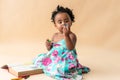 Nigerian baby girl sitting on the floor, holding and looking at a blue crayons